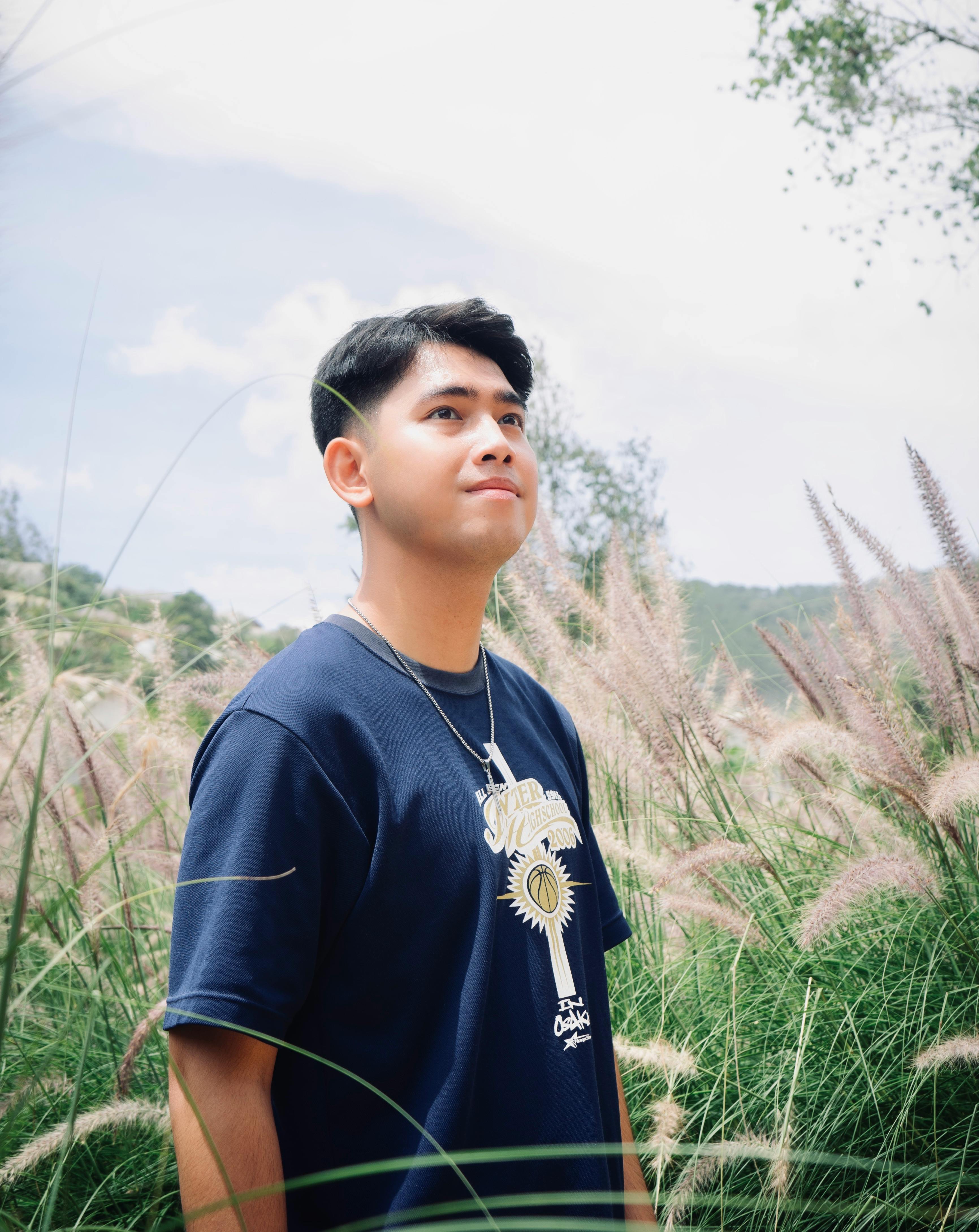 A young man smiling amidst tall grass in a sunny meadow, capturing the essence of summer outdoors.
