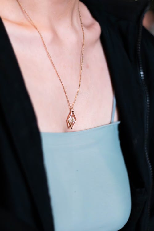 A woman wearing a necklace with a small heart on it