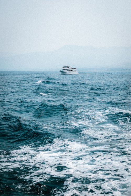 Free Distant ferry navigating through the ocean waves, showcasing a serene maritime scene. Stock Photo