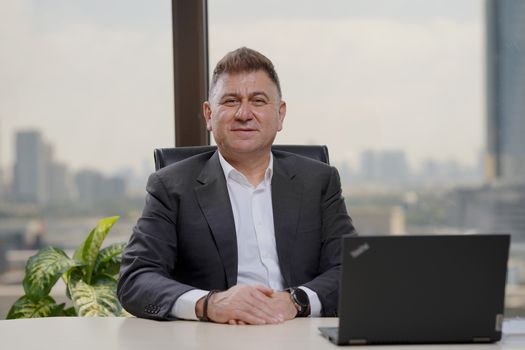 Confident middle-aged businessman in an elegant office with city view.