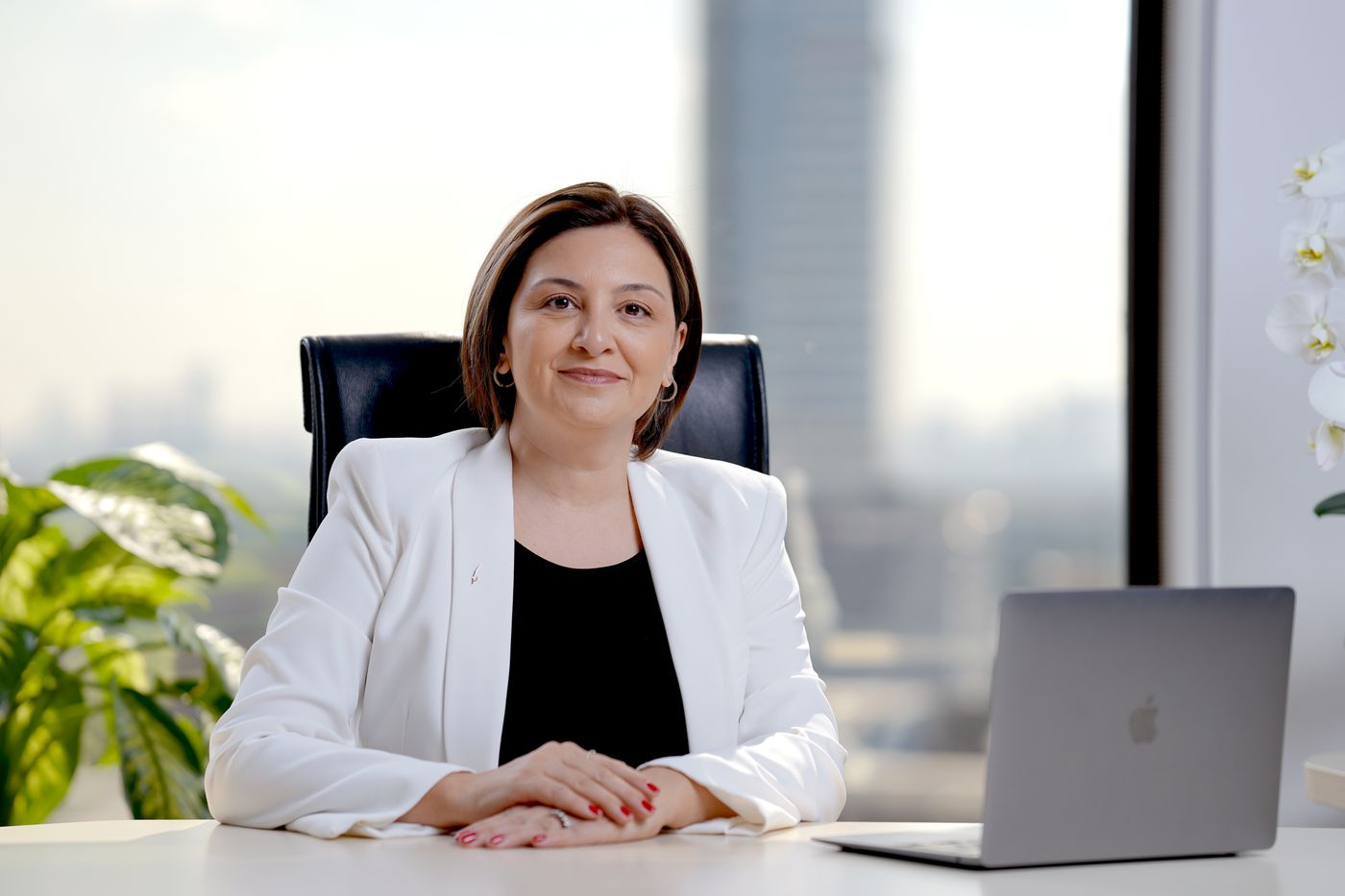 Smiling Indian professional woman at her office desk, representing healthy and engaged employees