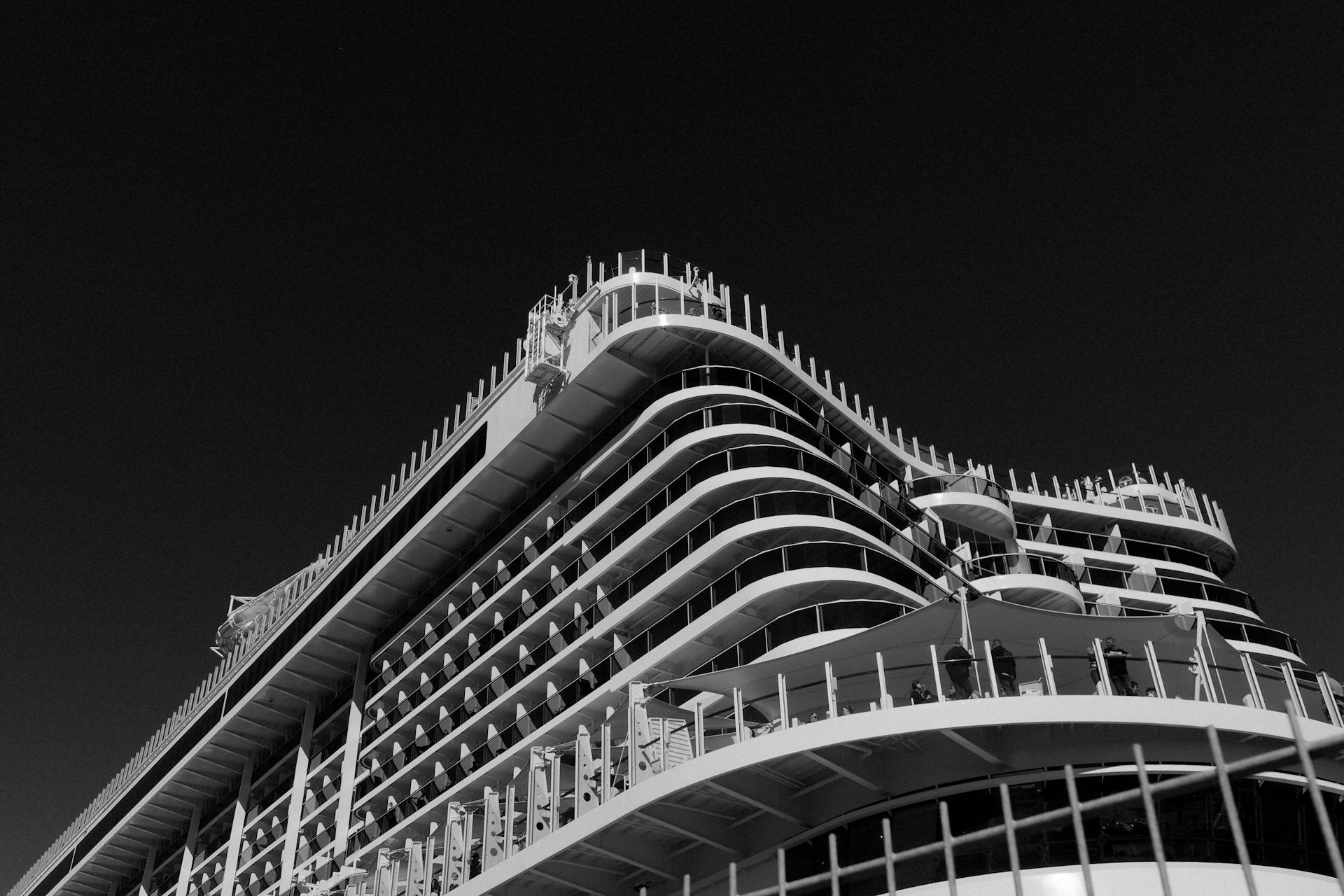 Dramatic low angle shot of a luxury cruise ship against a dark sky, emphasizing modern design.