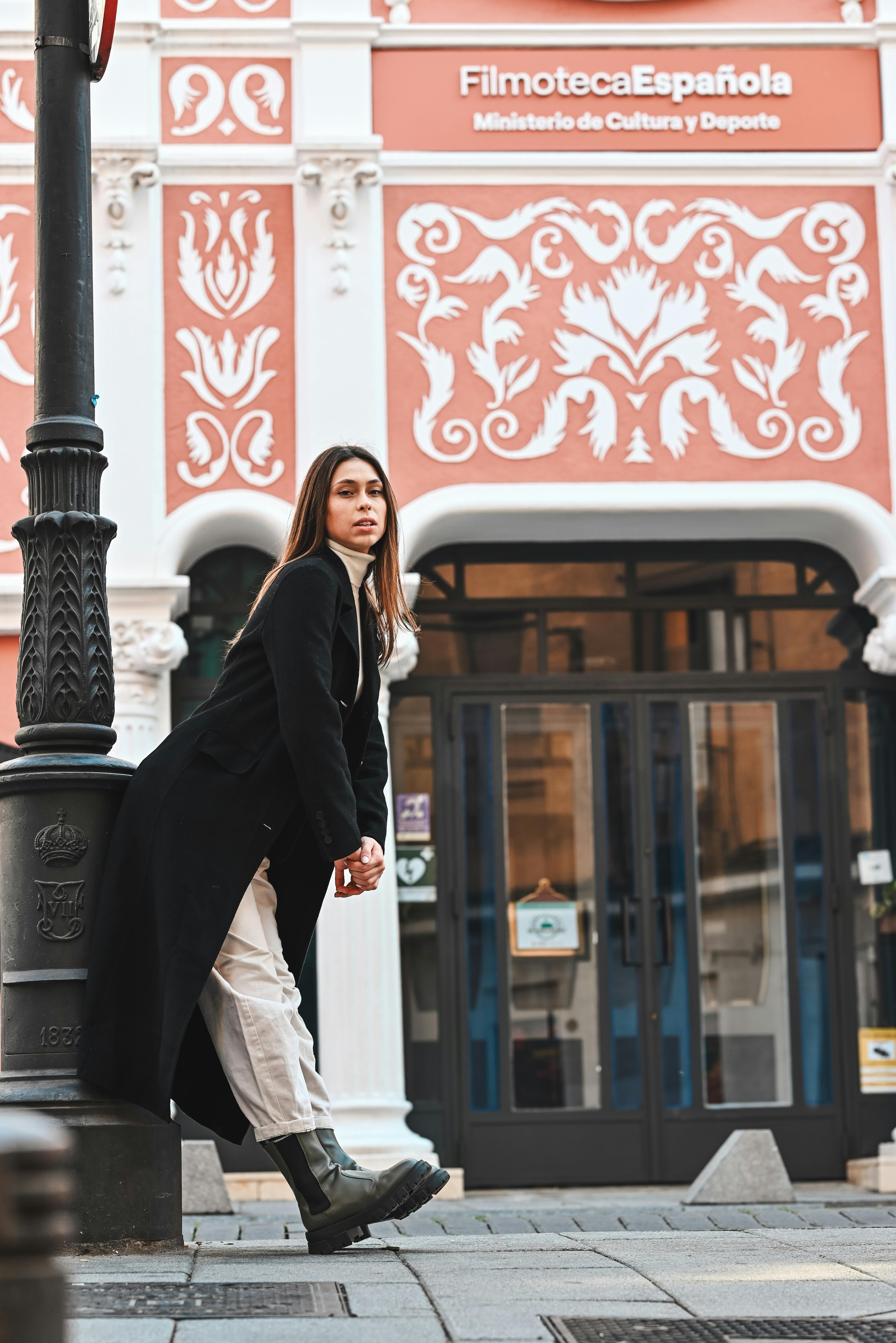 Free A woman in black coat leaning against a lamp post Stock Photo