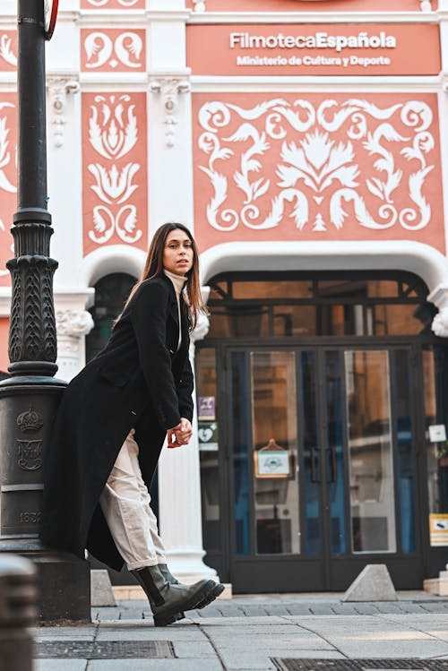 Free A woman in black coat leaning against a lamp post Stock Photo