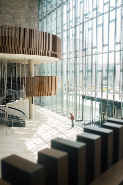 Free A person walking through a large building with a spiral staircase Stock Photo