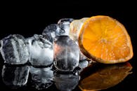 在黑暗背景下，一幅充满活力的静物画中摆放着新鲜的橙子片和冰块