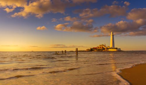 Free Breathtaking view of St Mary's Lighthouse on the English coast during a golden sunset. Stock Photo