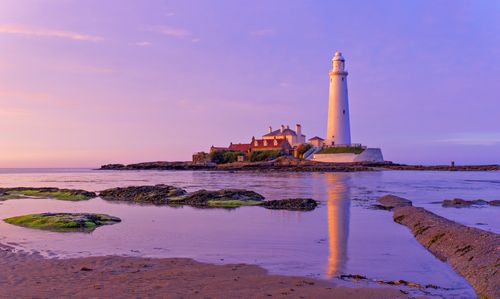 Free Calm sea and vibrant sunset at St Mary's Lighthouse on the Northumberland coast, UK. Stock Photo