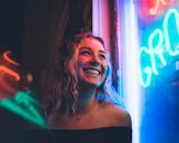 霓虹灯照亮了一位微笑女子的脸庞，捕捉到了充满活力的夜间氛围