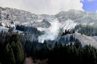 山间景色宁静，白雪皑皑，雾气缭绕，常绿树木点缀其间