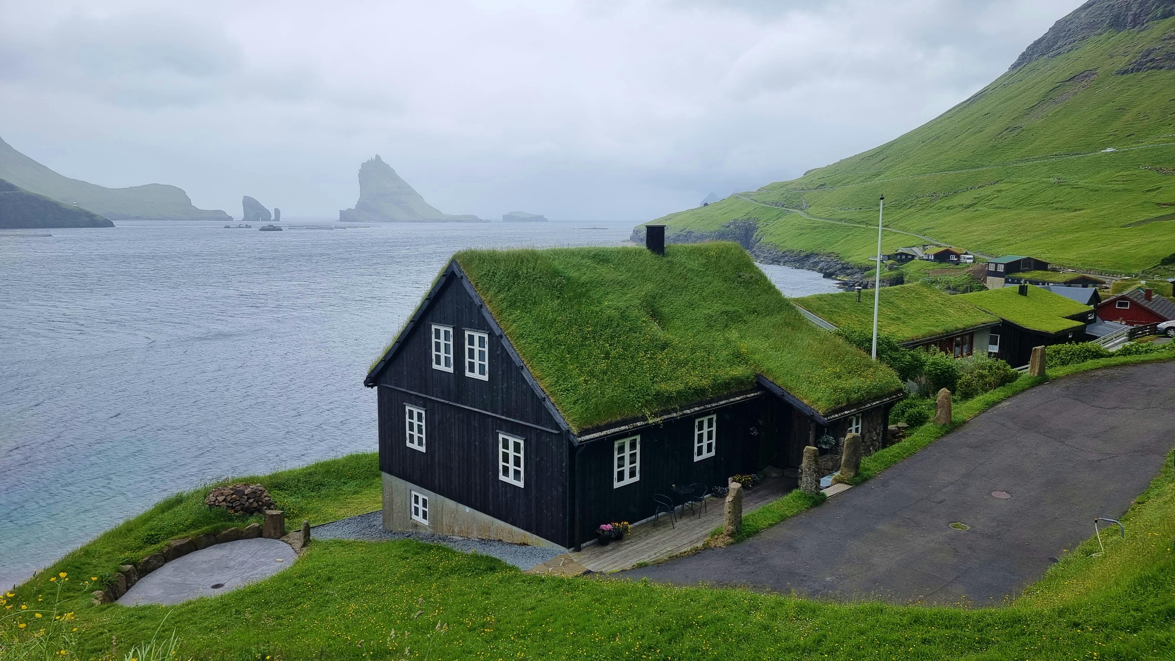 Charming grass-roofed house overlooking sea and mountains in Bøur village, Faroe Islands.