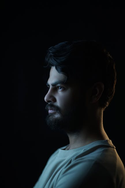 Portrait of a bearded man with dramatic studio lighting and a black background.