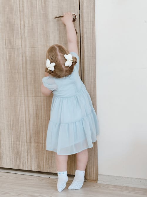 Free Girl in Dress Holding Reaching Door Handle Stock Photo