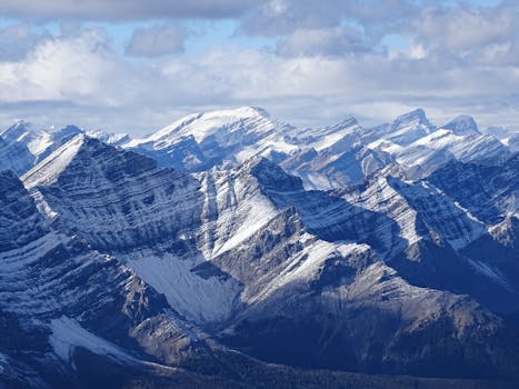 Majestic view of snow-capped Rocky Mountains under a cloudy sky in Banff National Park, Alberta.