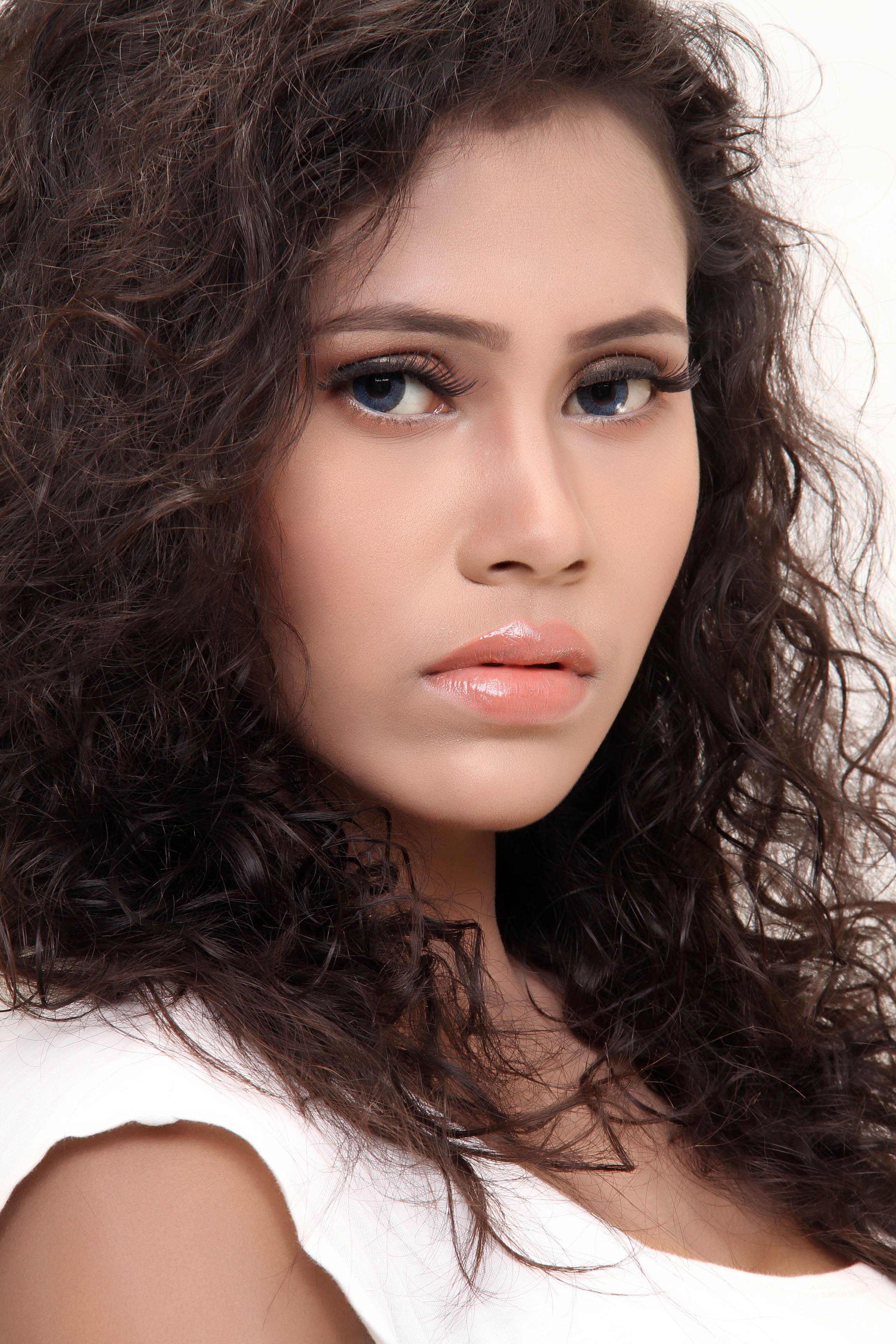 A detailed and expressive portrait of a woman with long, curly brown hair taken in a studio setting.