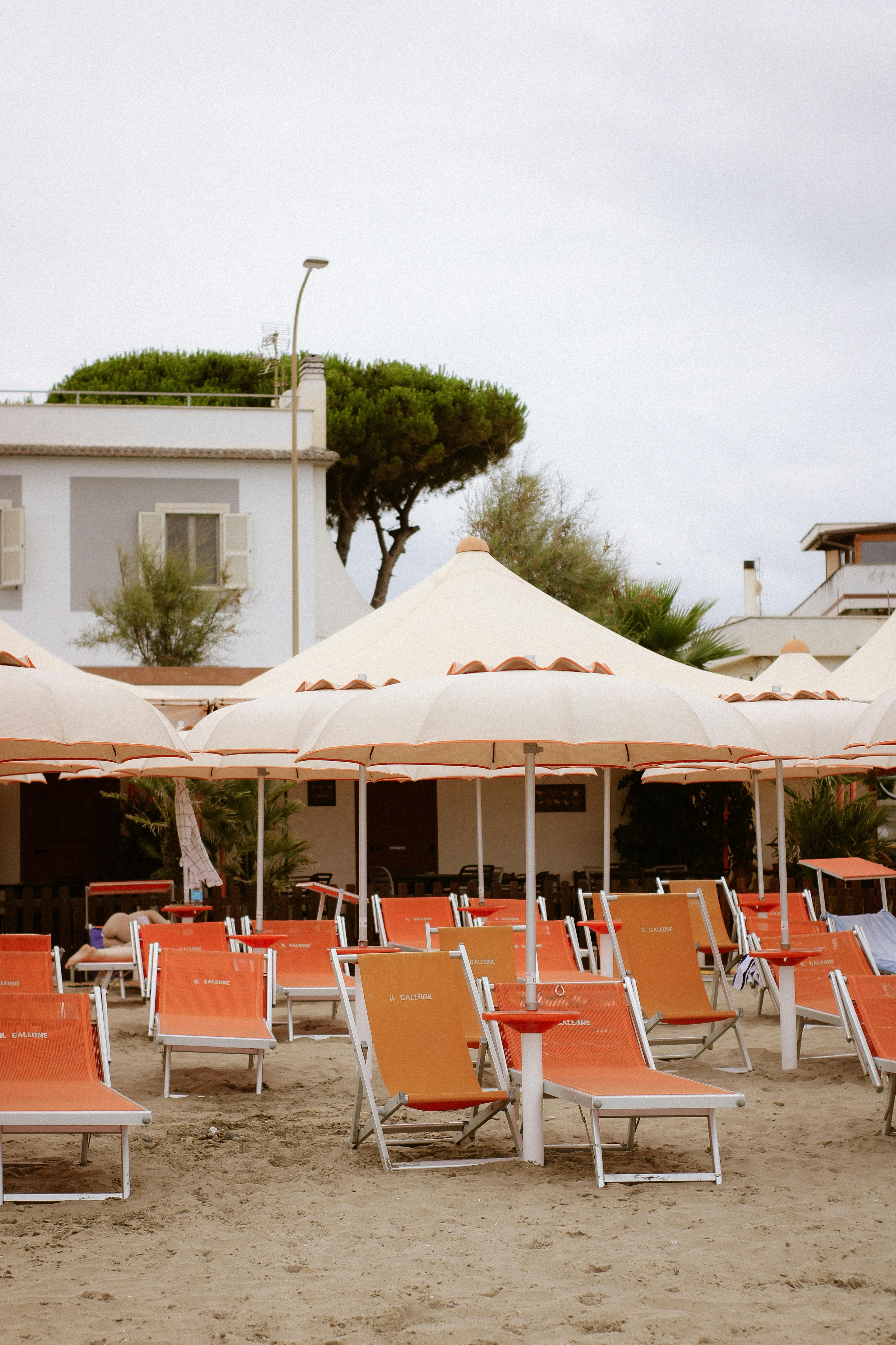 Inviting view of a sandy beach with orange sunbeds and parasols, perfect for a summer getaway.