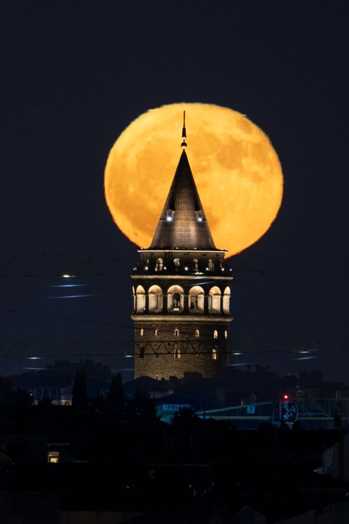 Free Stunning view of Galata Tower silhouetted by a full moon at night. Stock Photo