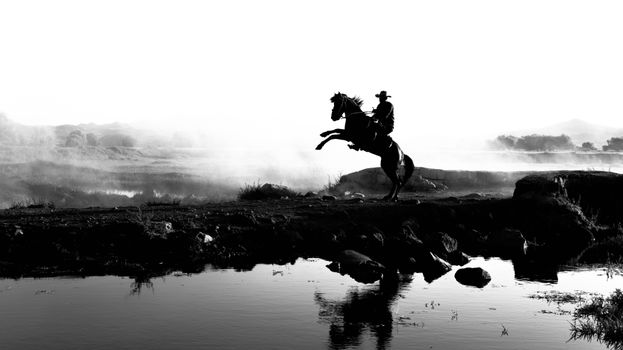 Dramatic black and white silhouette of a cowboy on a horse by a lakeside in Türkiye.
