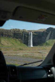 View of Seljalandsfoss Waterfall through car windshield, Icelandic landscape.