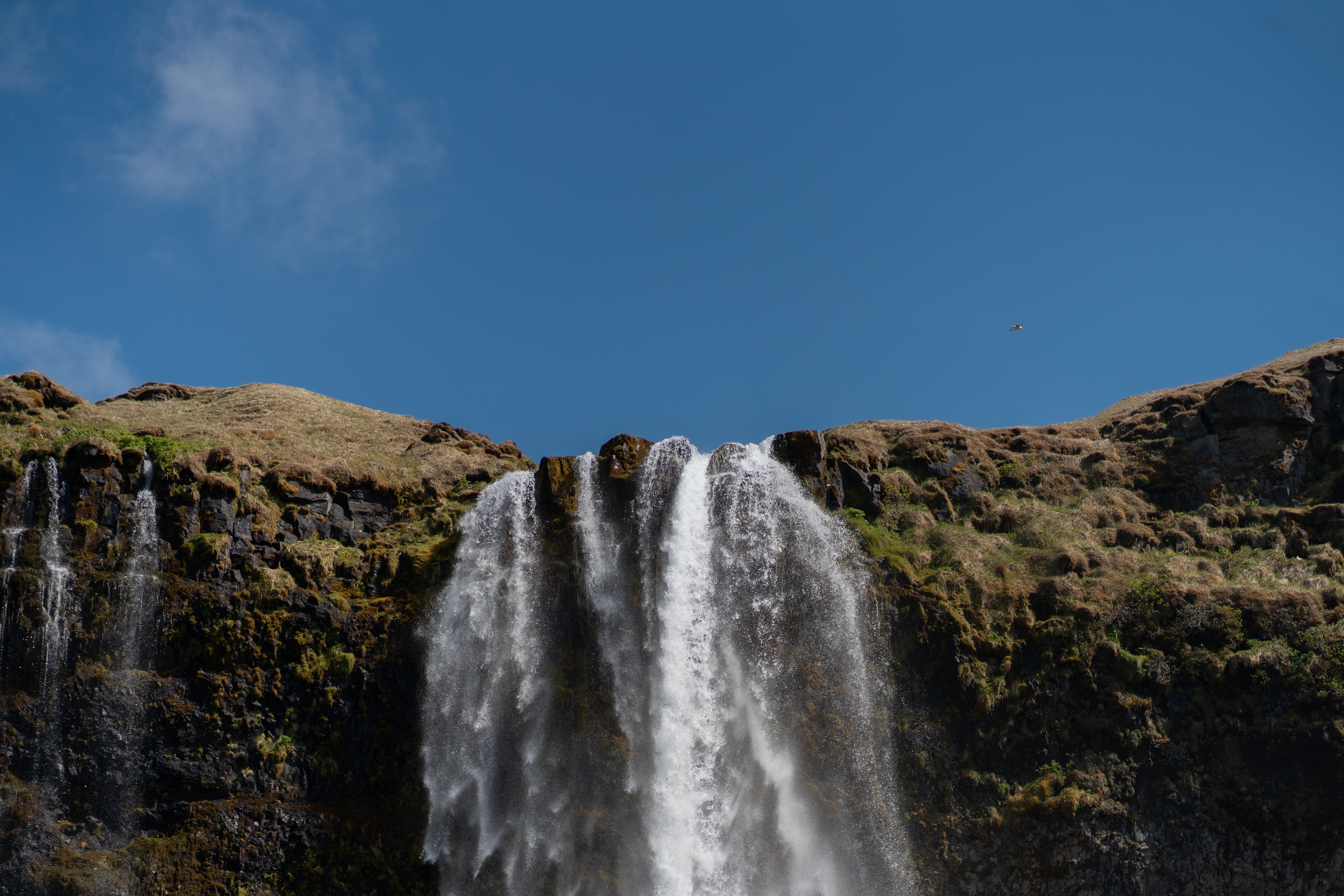 A waterfall is seen in the distance against a blue sky · Free Stock Photo