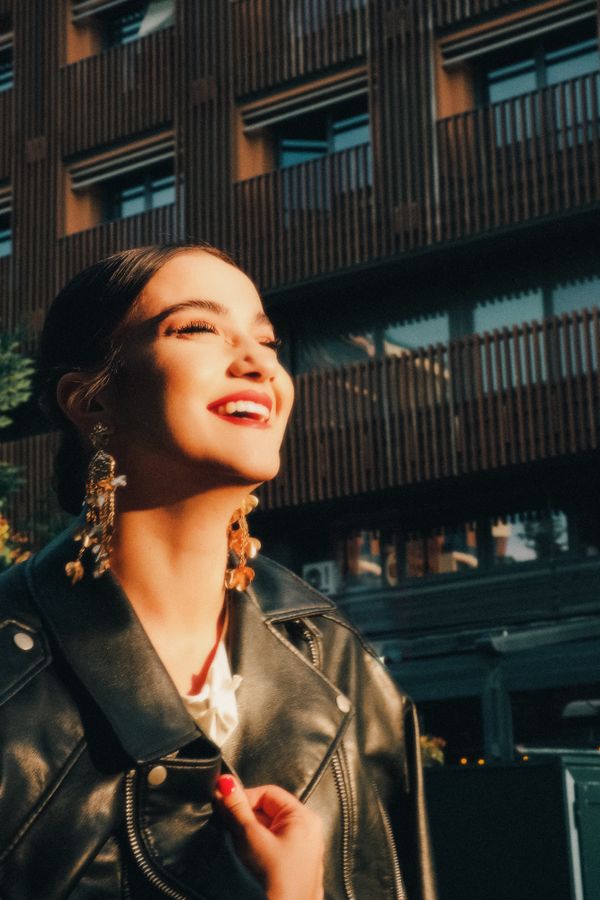 A smiling woman in a leather jacket in bright sunlight — photo by Ahmet İhsan Tezcan on Pexels