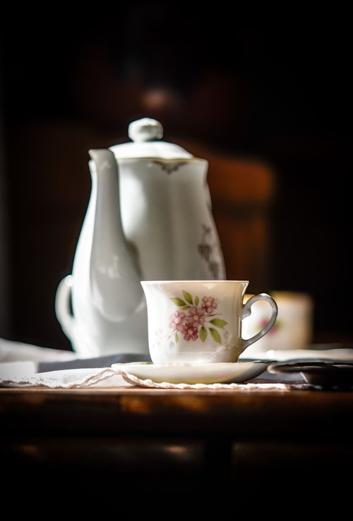 Free A charming setting with a floral porcelain teacup and teapot in soft lighting, creating a warm ambiance. Stock Photo