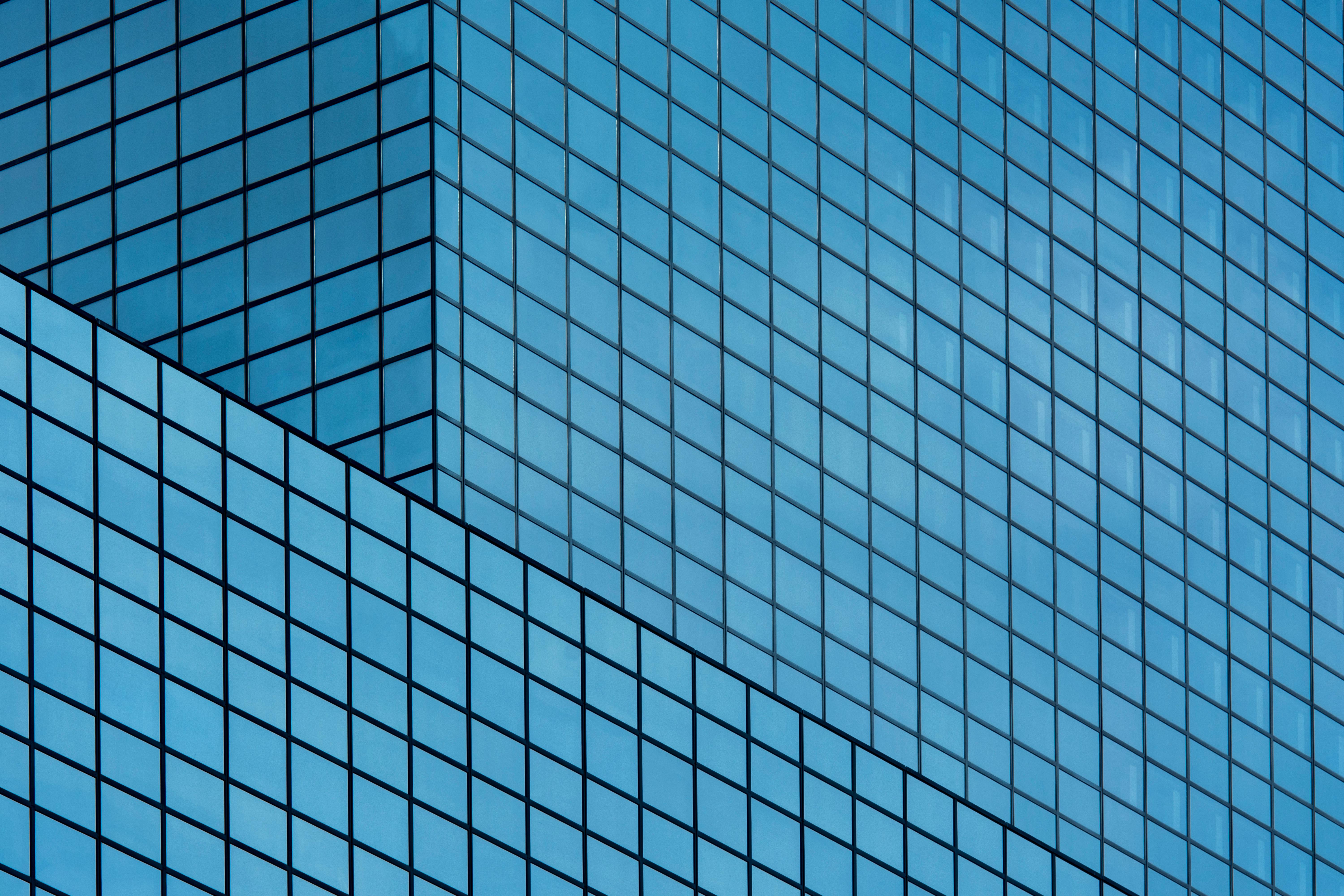 Close-up of modern glass skyscraper facade in Rotterdam, showcasing geometric patterns and reflections.