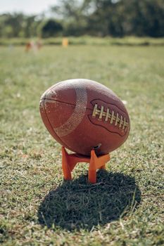 A detailed view of an American football resting on a grass field during daylight.