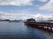 在宁静的湖景和多云的天空下，码头延伸向城市天际线