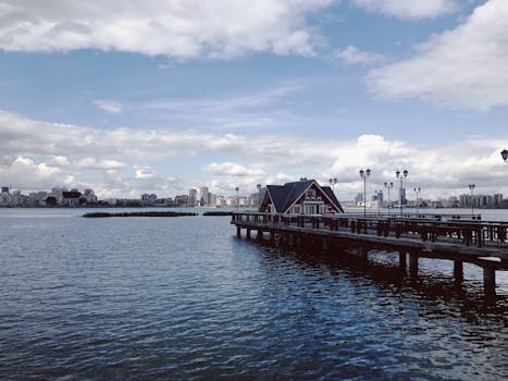 在宁静的湖景和多云的天空下，码头延伸向城市天际线