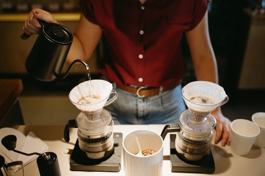 A barista carefully pours water in a café to prepare a perfect pour-over coffee.