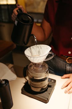 High angle view of barista carefully pouring water for perfect drip coffee at a café.