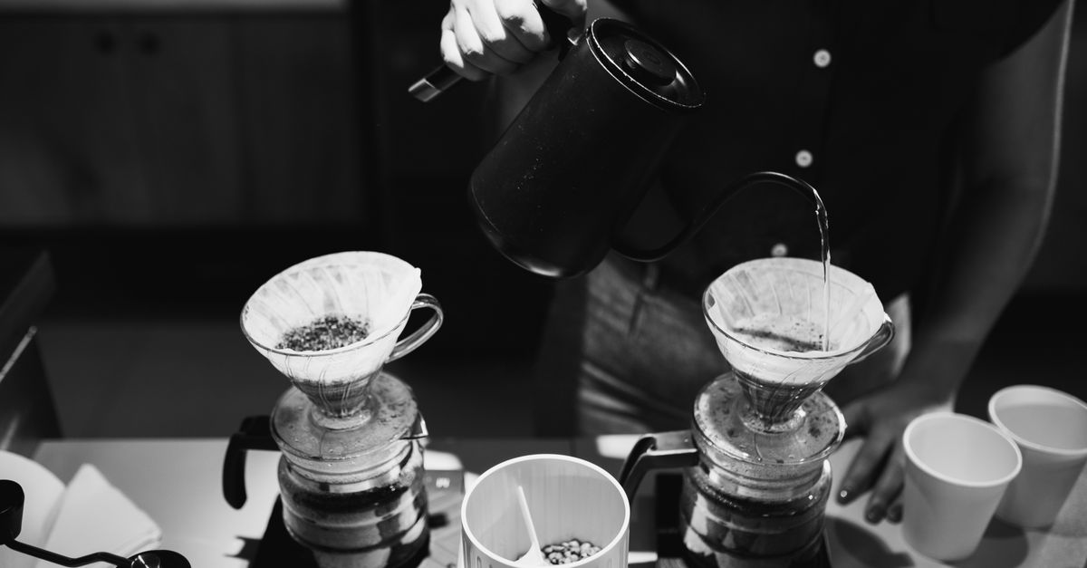 A barista artistically pouring coffee in a café setting, highlighting the brewing process.