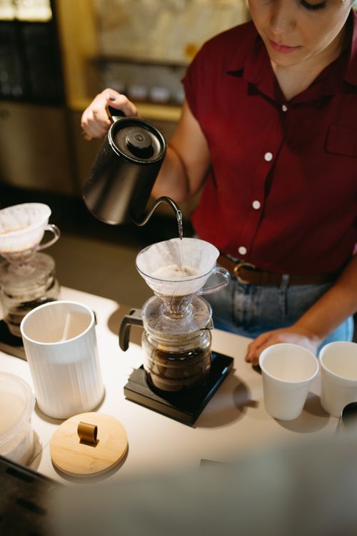 Free A barista expertly prepares coffee using the pour over method in a cafe setting. Stock Photo