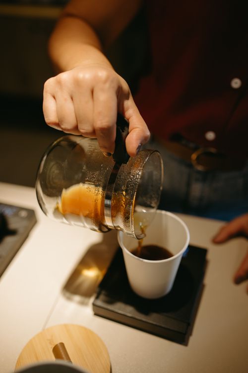 Free Close-up of barista pouring coffee into a cup on a scale at a café, showcasing the art of brewing. Stock Photo
