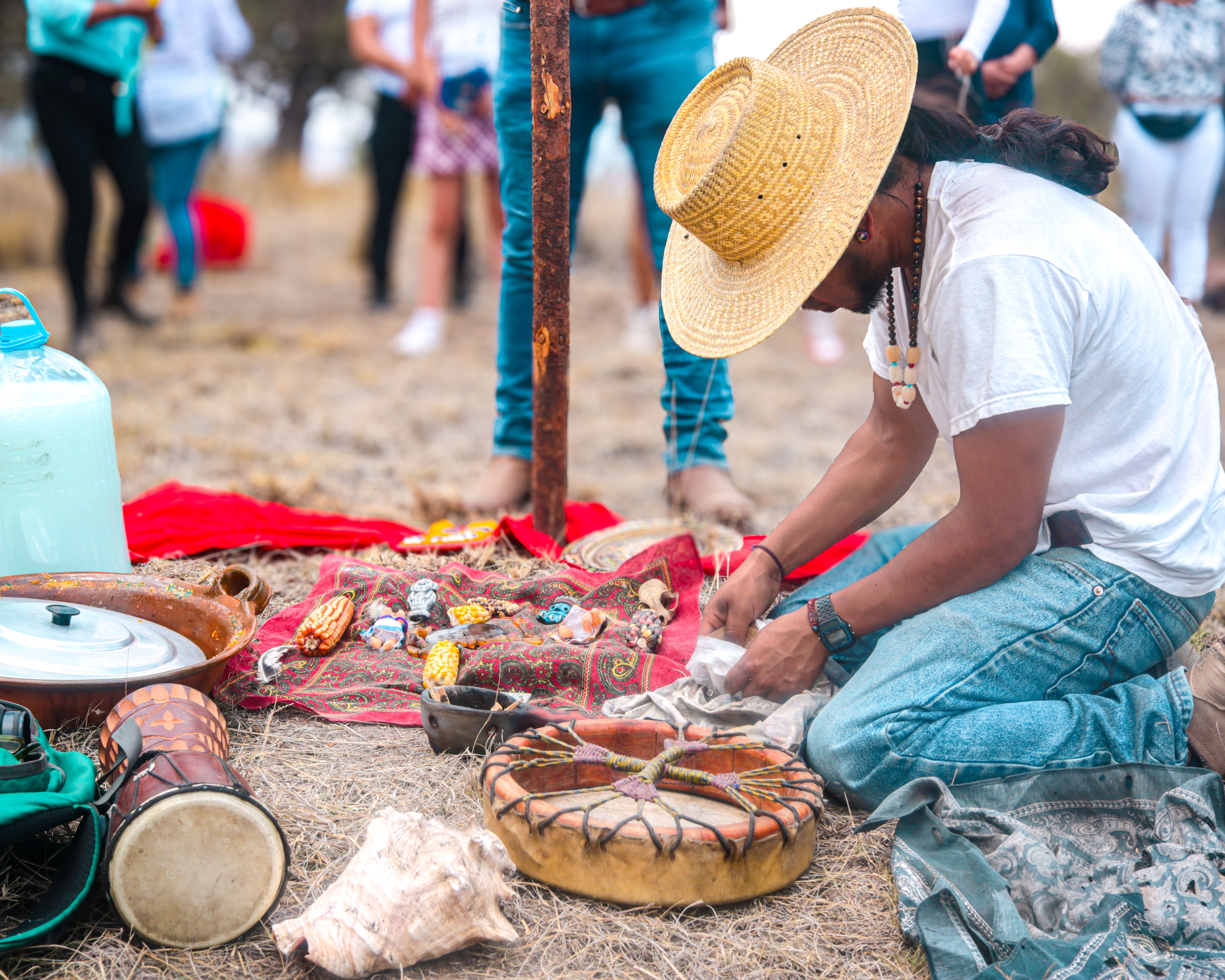 Man partakes in cultural ceremony outdoors with traditional instruments and attire.