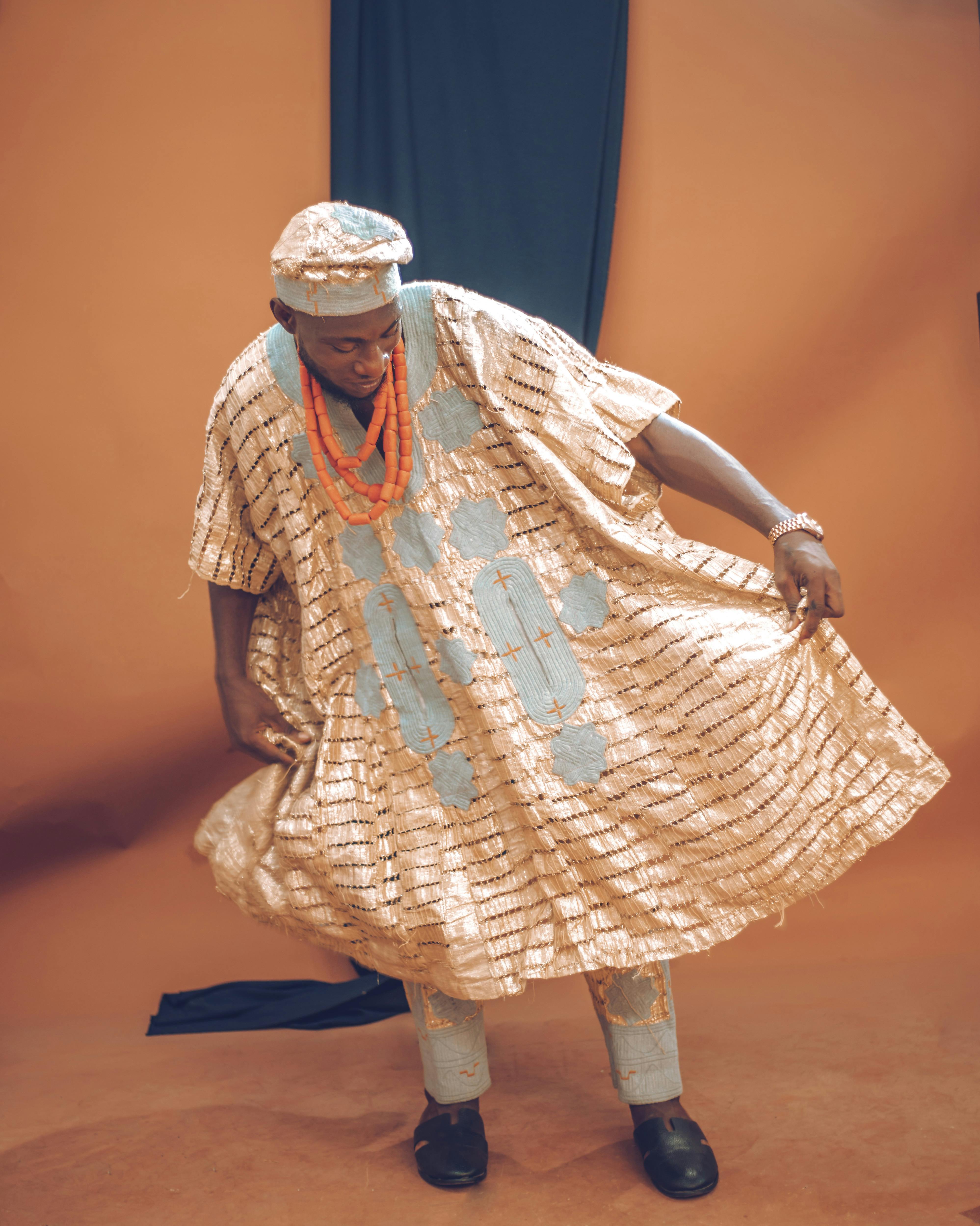 Man in traditional attire posing in a studio, showcasing cultural fashion.