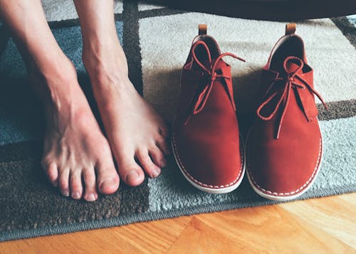 Free Person's Feet Beside Brown Shoes Stock Photo
