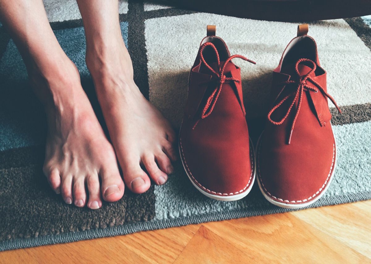 Blote voeten naast een paar rode leren veterschoenen