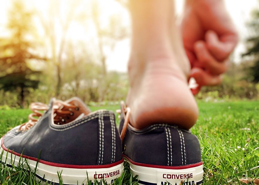 pexels photo 267229 Close-up of a barefoot person stepping into converse sneakers on grass in summer.