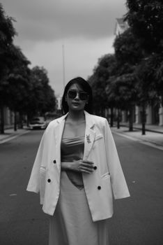 Stylish woman posing on a city street in a black and white urban setting.