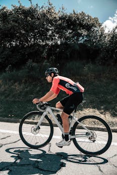 Focused cyclist rides on a road bike with a helmet, enjoying a sunny day outdoors.