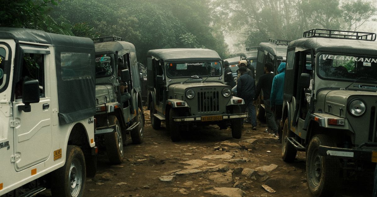 A line of rugged jeeps on a misty forest trail in Idukki, Kerala, India.
