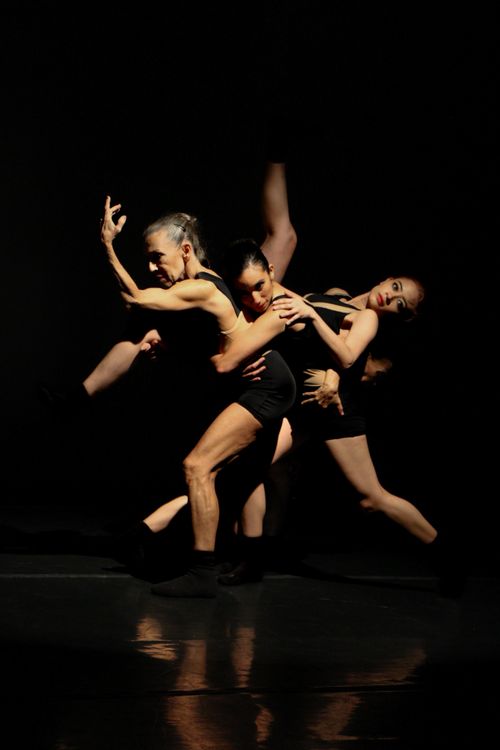 Free Energetic dancers performing a captivating ballet in a dark studio setting. Stock Photo