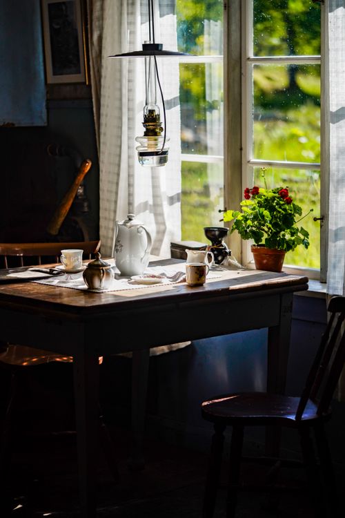 Free A cozy breakfast setting with rustic charm, featuring a table by a sunlit window adorned with vintage items and greenery. Stock Photo