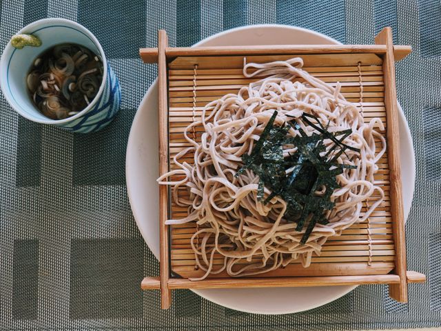 Top view of soba noodles served on a bamboo mat with a side of dipping sauce in Hakodate, Japan.