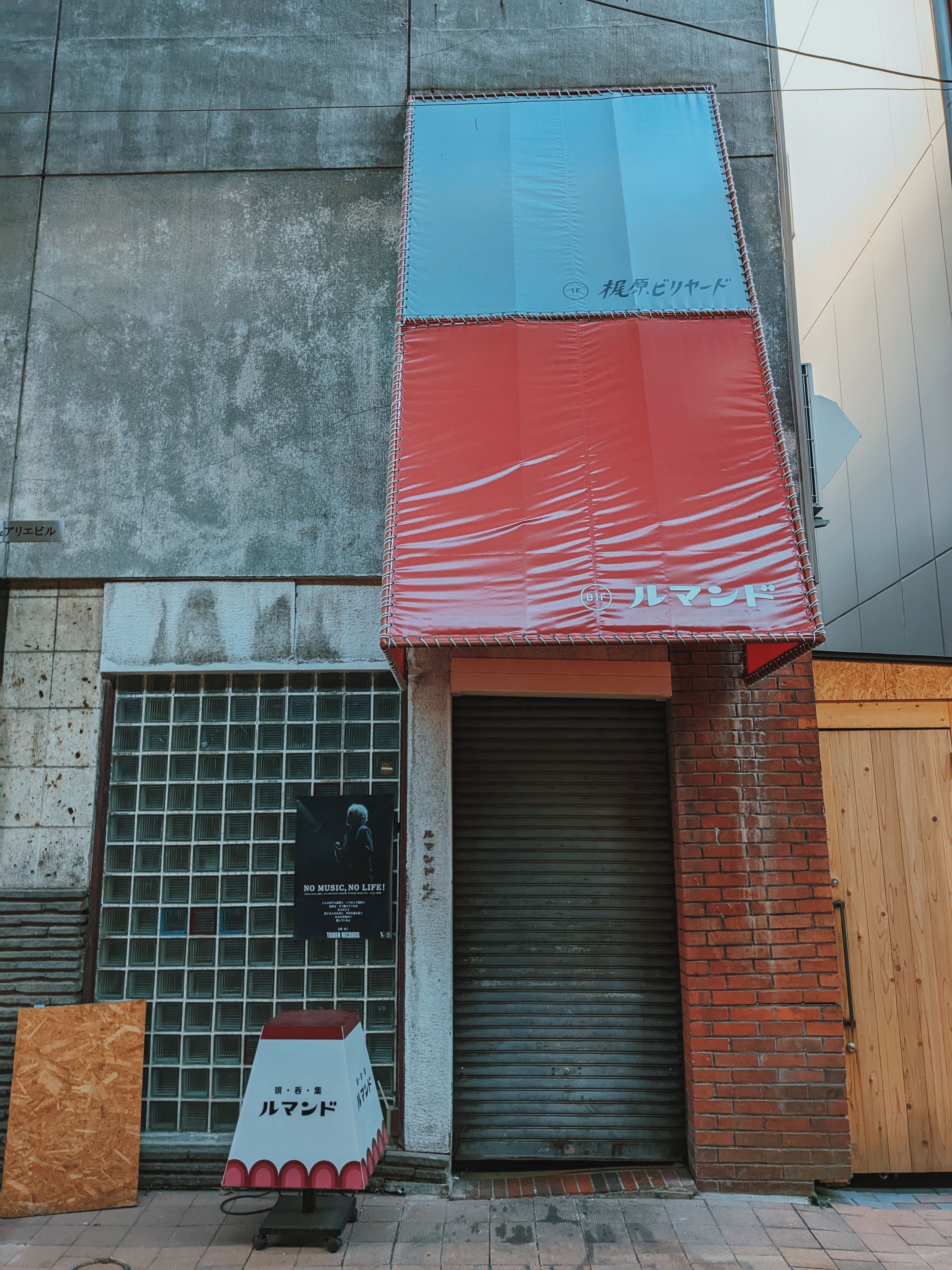 A street view in Sapporo, Japan showcasing a vibrant red and blue awning over a closed storefront.