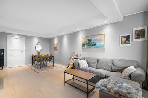 A living room with a grey couch and wooden flooring