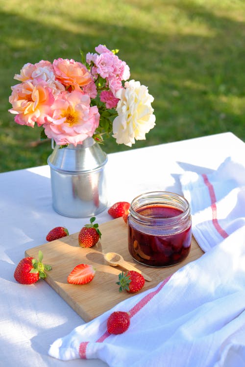 Free A jar of strawberry jam sits on a table with flowers Stock Photo