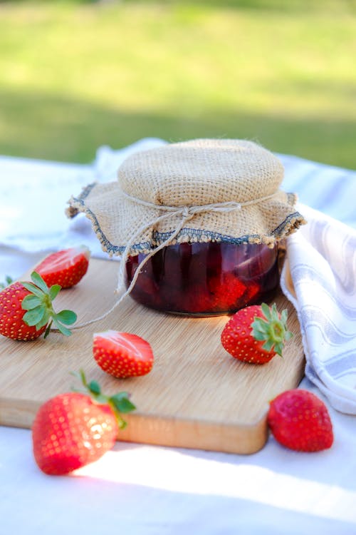 Free A jar of strawberry jam on a wooden cutting board Stock Photo